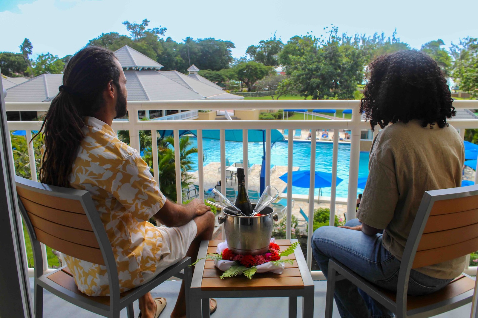 a man and woman sitting on a balcony with a bucket of wine